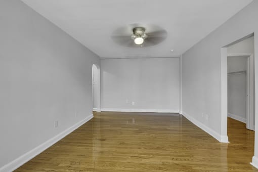 an empty living room with white walls and a ceiling fan