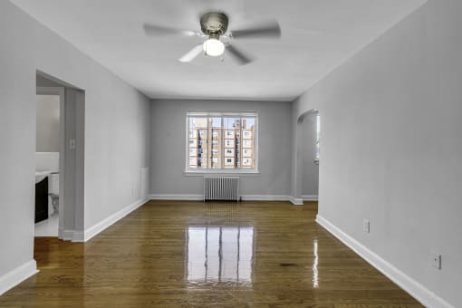 an empty living room with a ceiling fan and a window