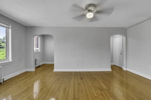 a living room with white walls and wood floors and a ceiling fan
