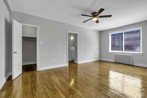 an empty living room with wood floors and a ceiling fan