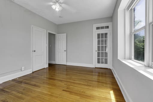 an empty living room with wood floors and two windows