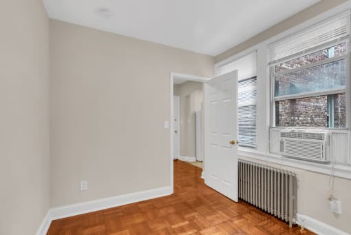 a living room with a large window and a radiator and a white door