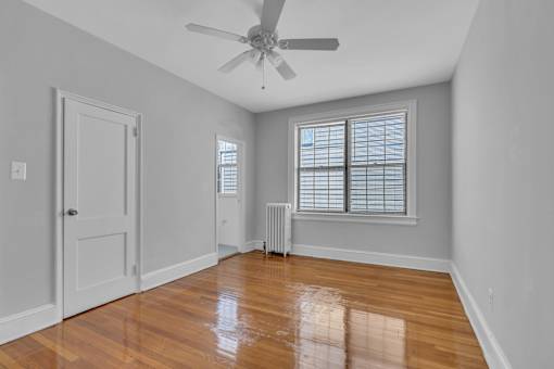 A room with a ceiling fan and a window with blinds.