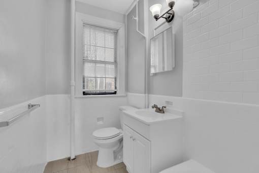 A white bathroom with a toilet, sink, and window.