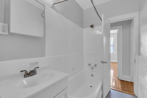 A white bathroom with a sink, tub, and shower.