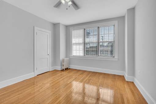 A room with a wooden floor and a window with blinds.