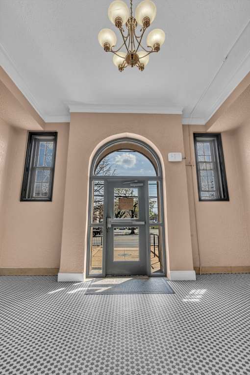 A hallway with a checkered floor and a chandelier.