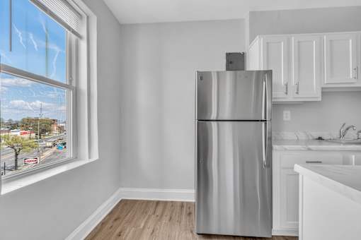 A kitchen with a stainless steel refrigerator and white cabinets.