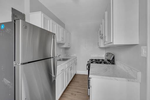 A kitchen with white cabinets and a stainless steel refrigerator.