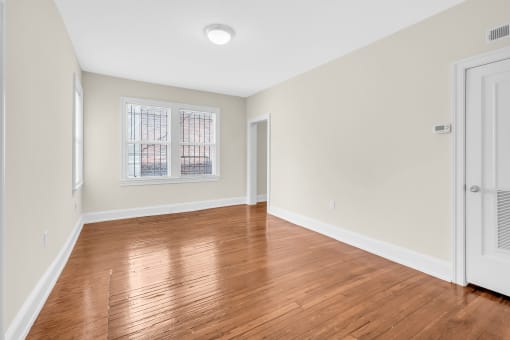 an empty living room with wood floors and a window
