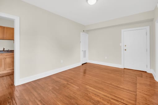 an empty living room with wood flooring and white walls