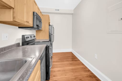 an empty kitchen with stainless steel appliances and wood flooring