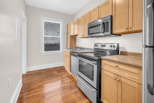 an empty kitchen with wooden cabinets and stainless steel appliances