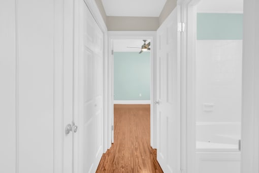 a hallway with white doors and a ceiling fan