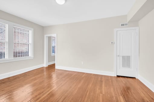 an empty living room with wood floors and a white door
