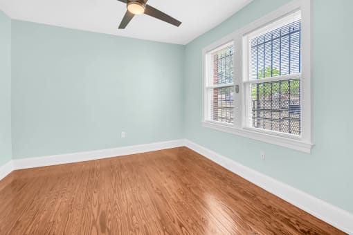 an empty room with wood floors and a ceiling fan