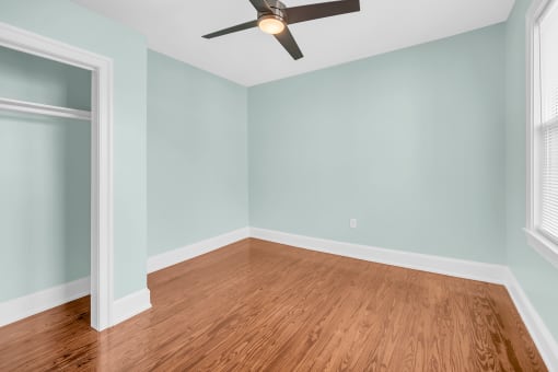 an empty room with blue walls and a ceiling fan