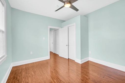 an empty room with blue walls and a ceiling fan