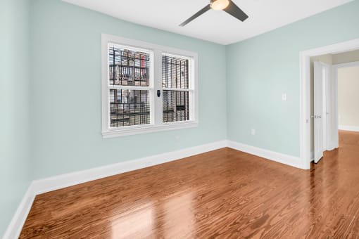 an empty room with blue walls and a window and wooden floors