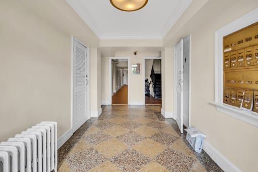 the hallway of a house with white doors and a tiled floor