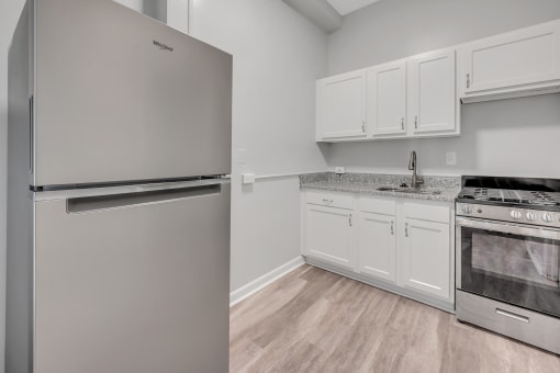 an empty kitchen with stainless steel appliances and white cabinets
