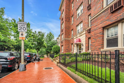 a sidewalk in front of a brick building with a speed limit sign