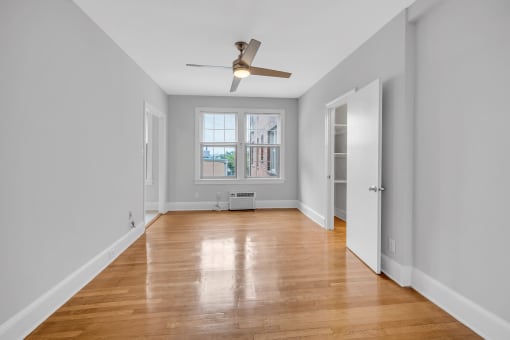 an empty living room with a ceiling fan and a window
