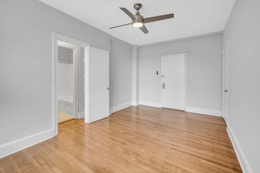 an empty living room with wood floors and a ceiling fan