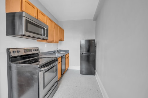 an empty kitchen with stainless steel appliances and wooden cabinets