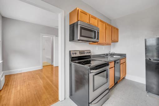an empty kitchen with stainless steel appliances and wooden cabinets