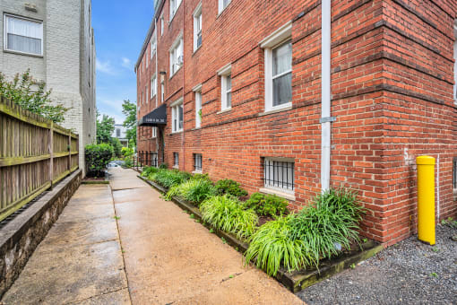 a brick building with a sidewalk and a yellow pole
