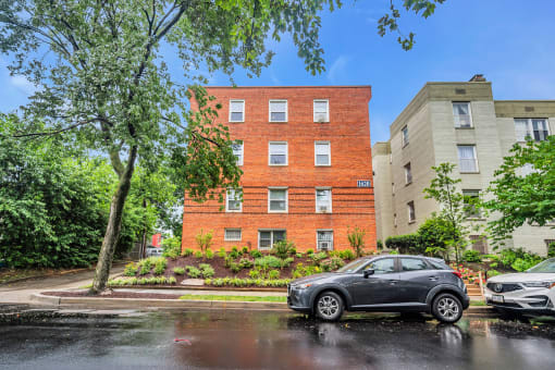 an apartment building on a rainy street with a car parked in front