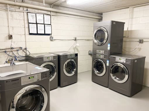 A row of industrial washing machines in a laundry room.