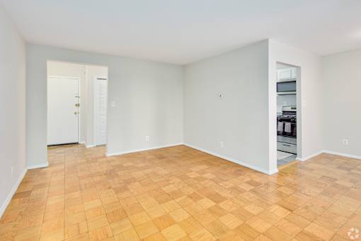 Empty room with wooden flooring and white walls.