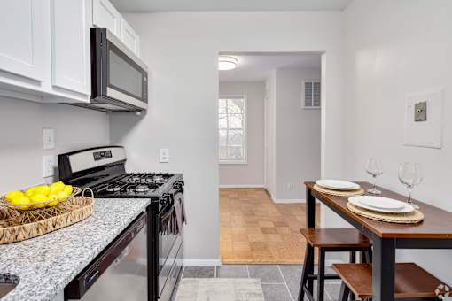 A kitchen with a black stove top oven and a black microwave above it.