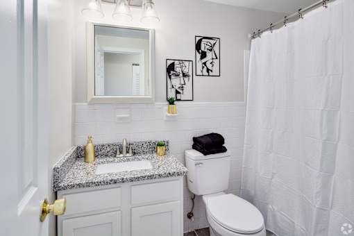A white bathroom with a toilet, sink, and shower.