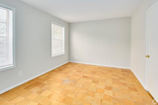 A room with wooden flooring and a window with blinds.