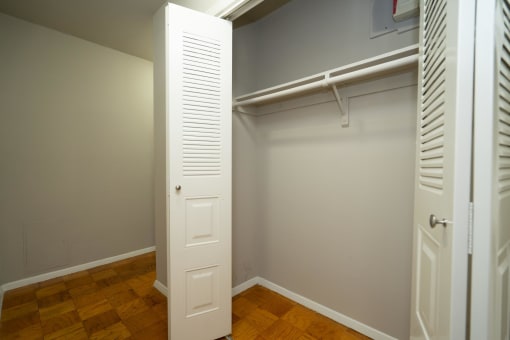 a closet in a bedroom with a wooden floor and white closet doors