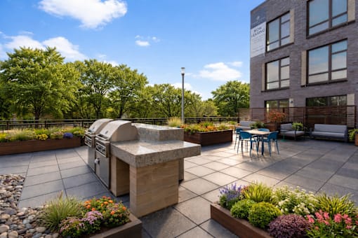 A patio with a table and chairs and a barbecue grill.