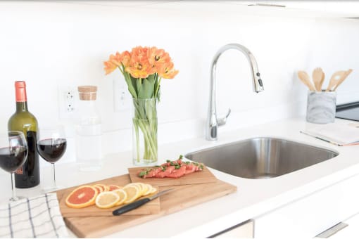 a kitchen sink with a cutting board with sliced citrus and a vase of flowers