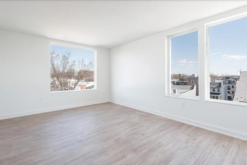 a bedroom with a hardwood floor and three windows