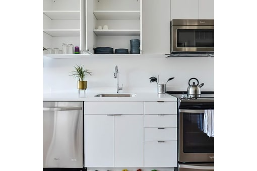 a small kitchen with white cabinets and stainless steel appliances