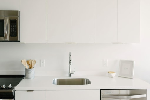 a kitchen with white cabinets and a stainless steel sink