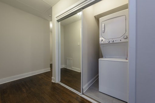 a white washer and dryer in a room with a mirror and a door