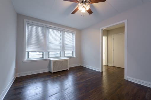 an empty living room with wood floors and a ceiling fan
