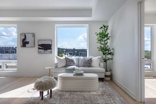 A living room with a white couch, a small table, and a large window.