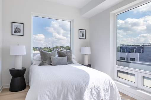 A bedroom with a large bed, two lamps, and pictures on the wall.