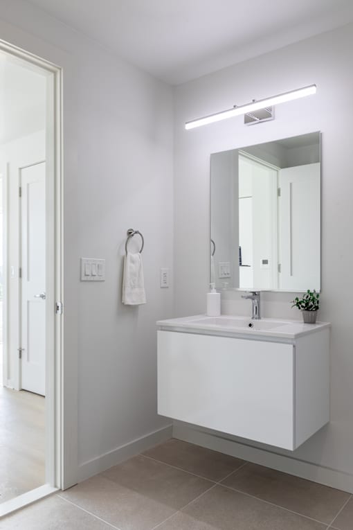 A white bathroom sink with a mirror and a light above it.