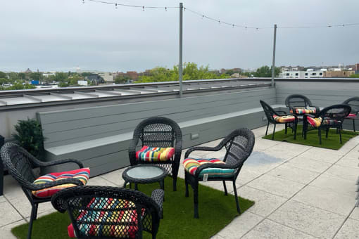 an outdoor patio with chairs and tables on top of a building