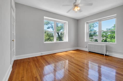an empty living room with wood floors and a ceiling fan